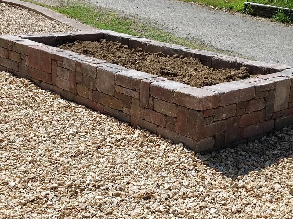 A brick planter is sitting on top of a pile of gravel.