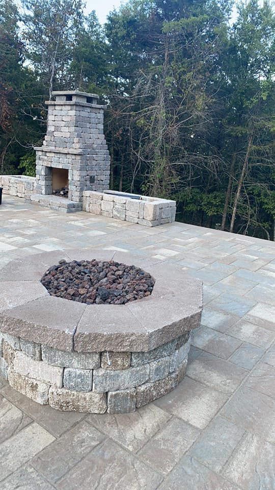 A fire pit is sitting on top of a patio next to a fireplace.