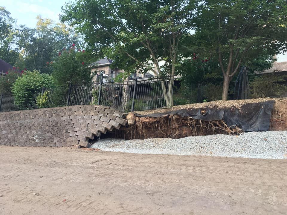 A large rock wall is being built in the middle of a dirt field.