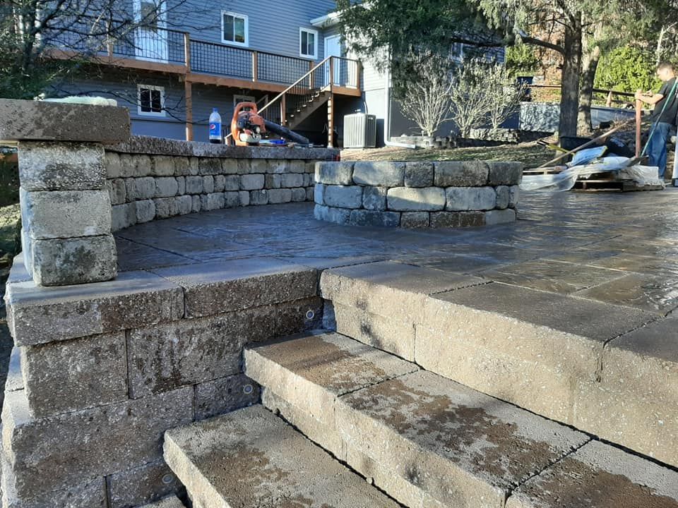 A stone wall and stairs are being built in front of a house.