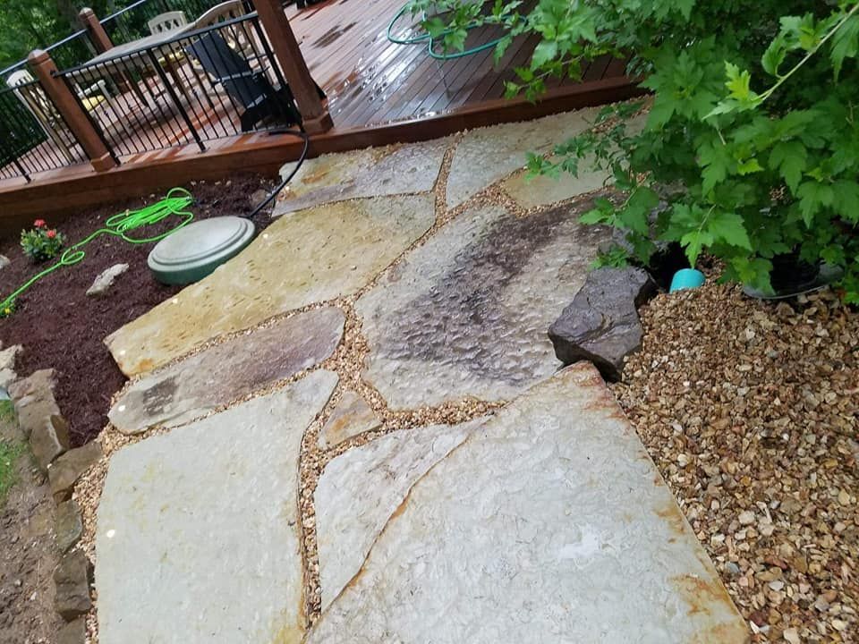 A stone walkway with a wooden deck in the background.