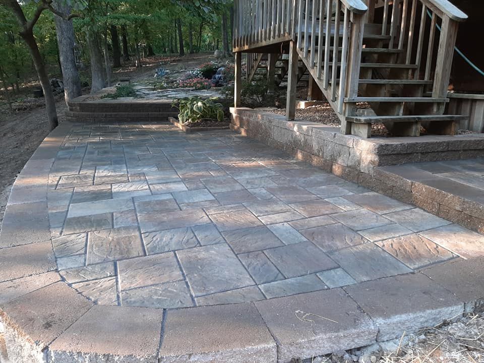 A patio with stairs leading up to a wooden deck.