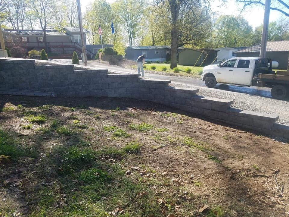 A white truck is parked on the side of the road next to a concrete wall.