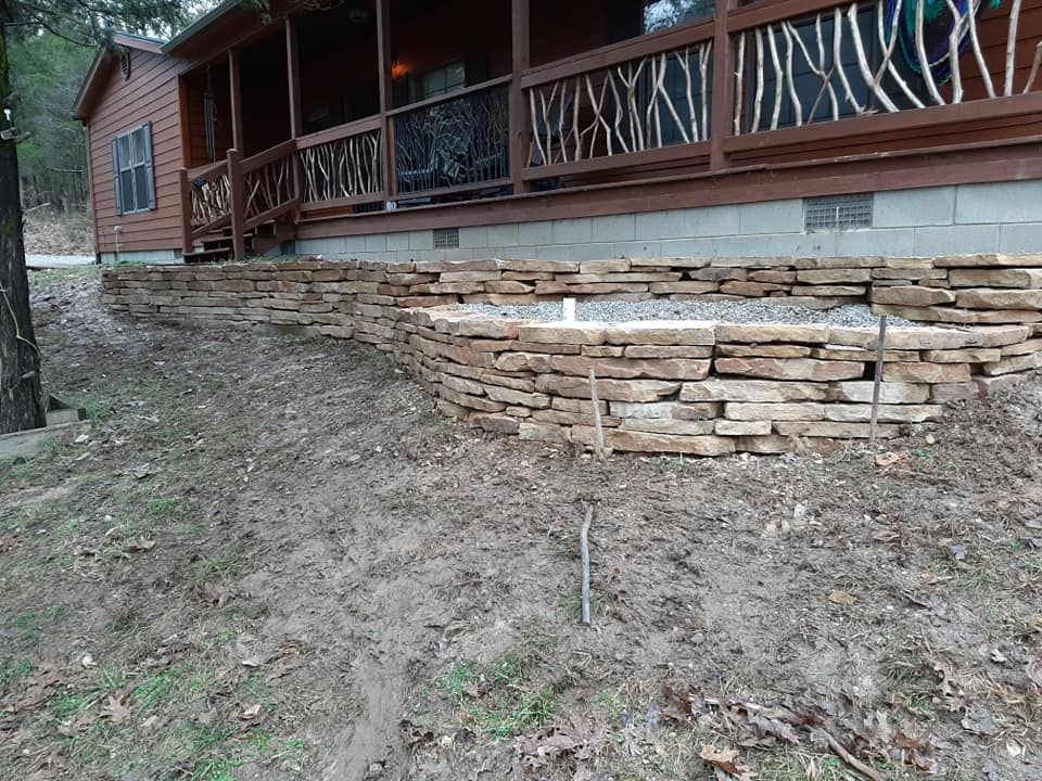 A stone wall is being built in front of a house.