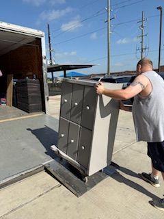 A man is lifting a dresser out of a truck.