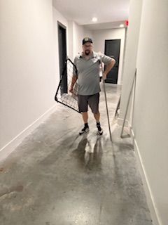 A man is standing in a hallway holding a soccer net.
