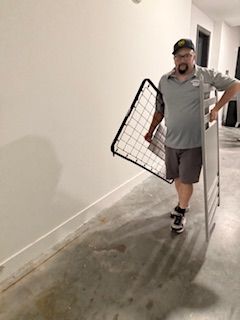 A man is carrying a mattress in a hallway.