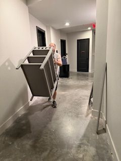 A man is carrying a chair down a hallway.