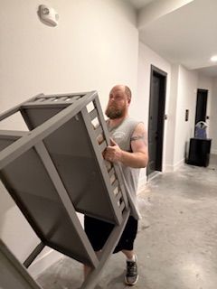 A man is carrying a chair in a hallway.