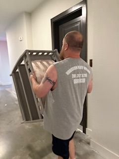A man is carrying a chair in a hallway.