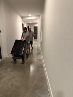 Two men are pushing a black box down a hallway.
