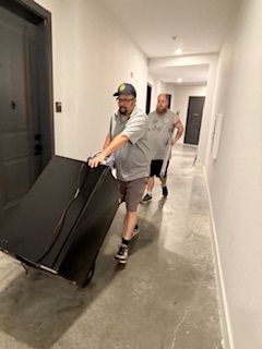 Two men are pushing a refrigerator down a hallway.