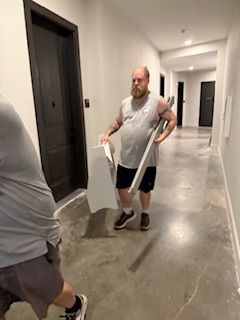 A man is carrying a piece of wood in a hallway.