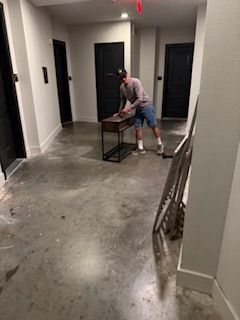 A man is standing in a hallway cleaning a table.