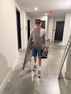 A man is walking down a hallway carrying a toolbox and a fence.