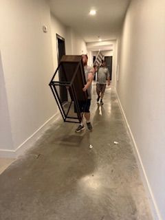 Two men are carrying a table down a hallway.