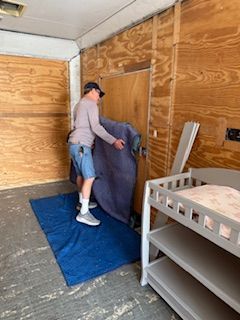 A man is standing on a blue mat in a room next to a changing table.