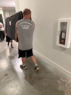 A man is carrying a large piece of furniture down a hallway.