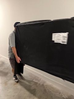 A man is carrying a large black object on his back.