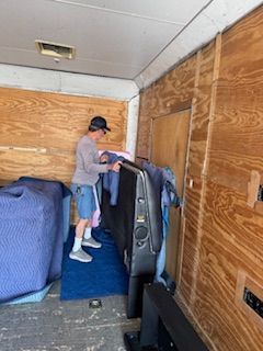 A man is carrying a television in a trailer.