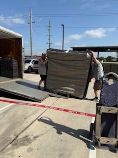 Two men are carrying a mattress out of a truck.