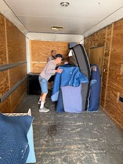 A man is pushing a mattress into a moving truck.