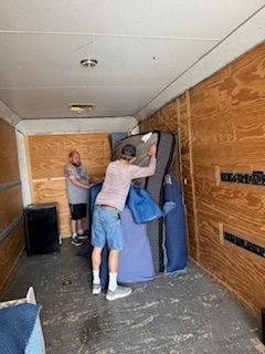 Two men are moving a piano into a trailer.