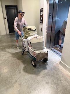 A man is pushing a cart full of laundry into an elevator.