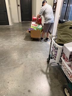 A man is pushing a cart full of boxes in a garage.