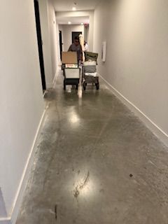 A man is pushing a cart with boxes in a hallway.