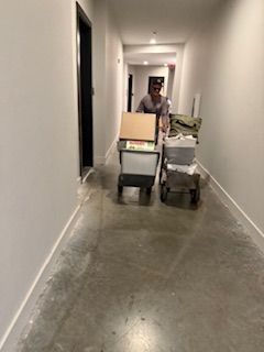 A person is pushing a cart with boxes on it down a hallway.