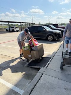 A man is pushing a cart full of boxes in a parking lot.
