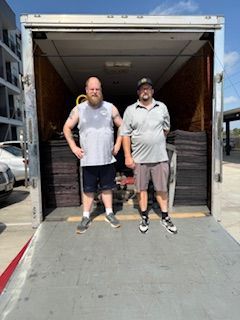 Two men are standing in front of a moving truck.