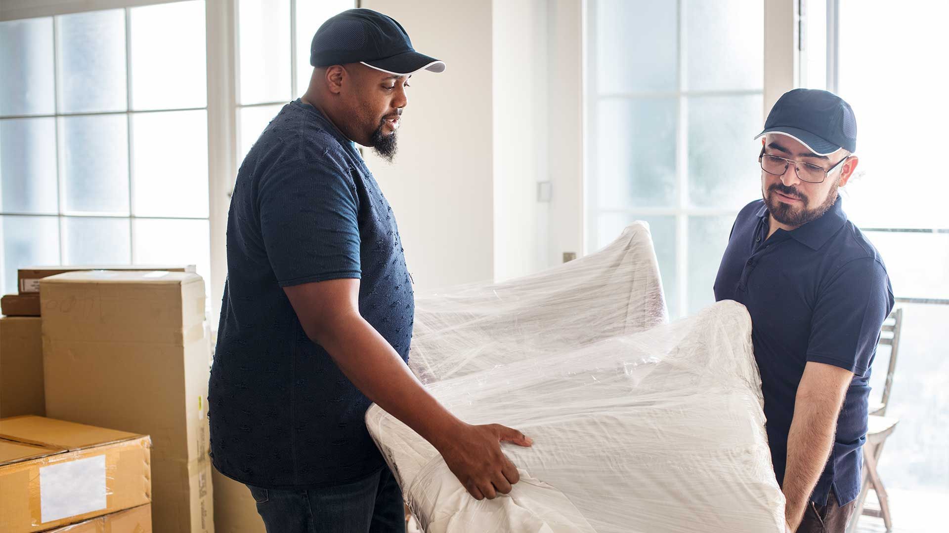 Two men are moving a couch in a living room.