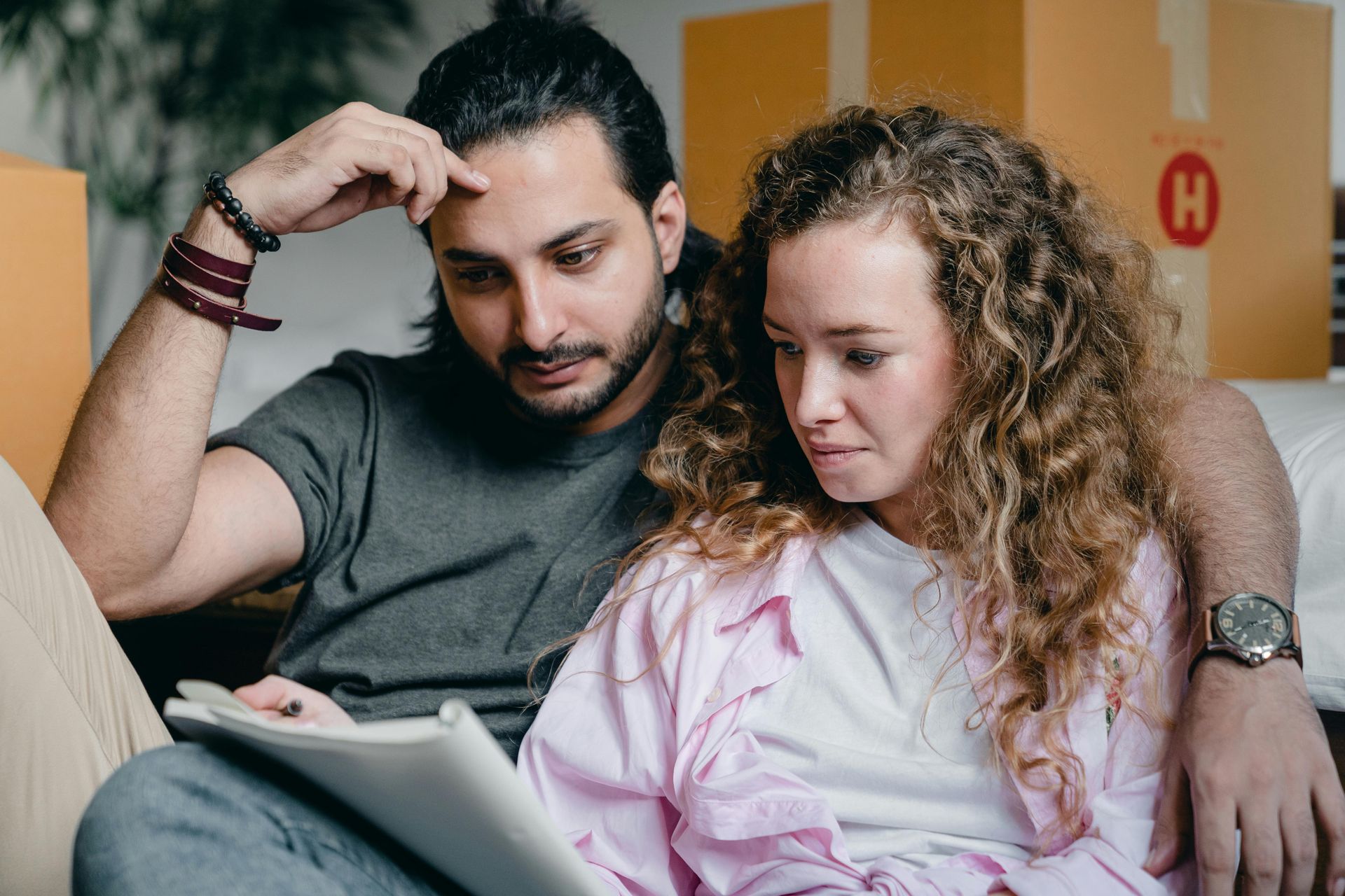 A man and a woman are sitting on a couch looking at a tablet.