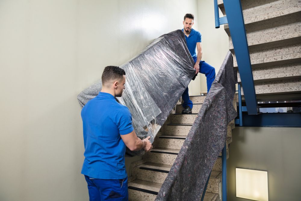 Two men are carrying a large piece of furniture up a set of stairs.