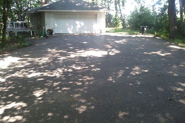A driveway leading to a garage with trees in the background