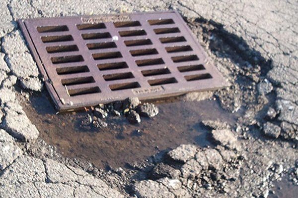 A manhole cover is sitting on a cracked road