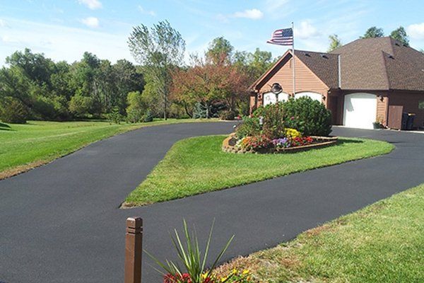 A driveway leading to a house with a flag on the roof