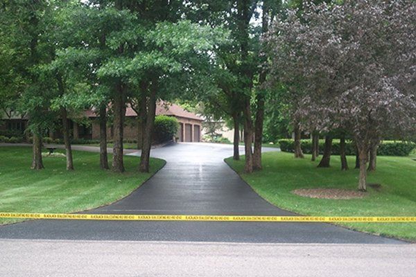 A driveway leading to a house with trees on both sides