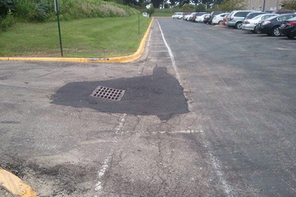 A parking lot with a drain hole in the middle of it.