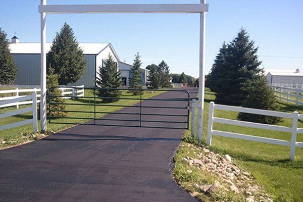 A driveway with a gate and a white fence