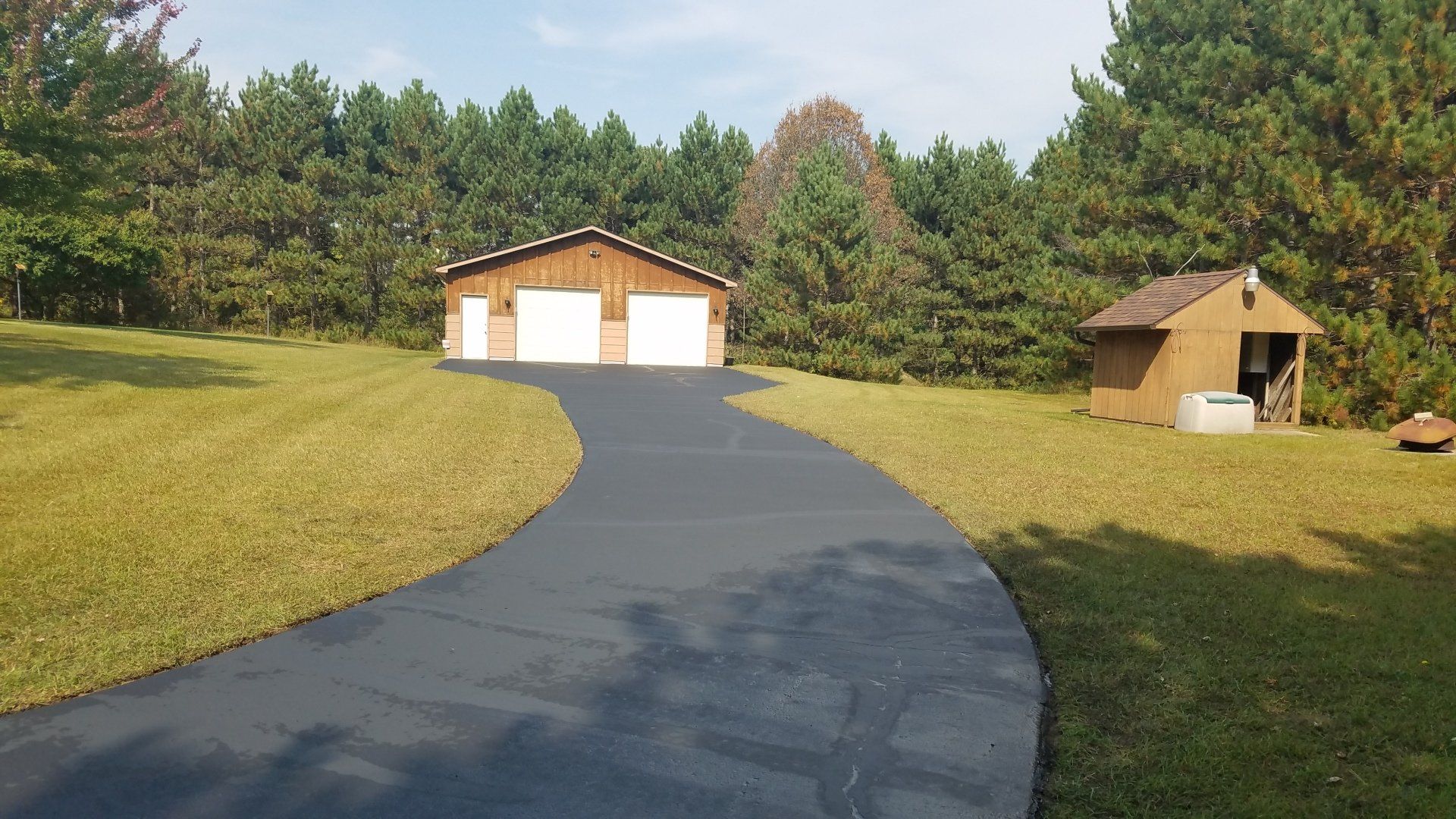 A driveway leading to a garage in the middle of a grassy field.