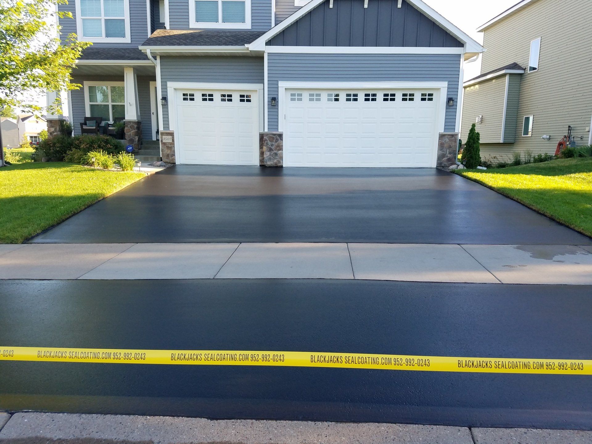 A driveway with a house in the background and a yellow tape on the sidewalk.