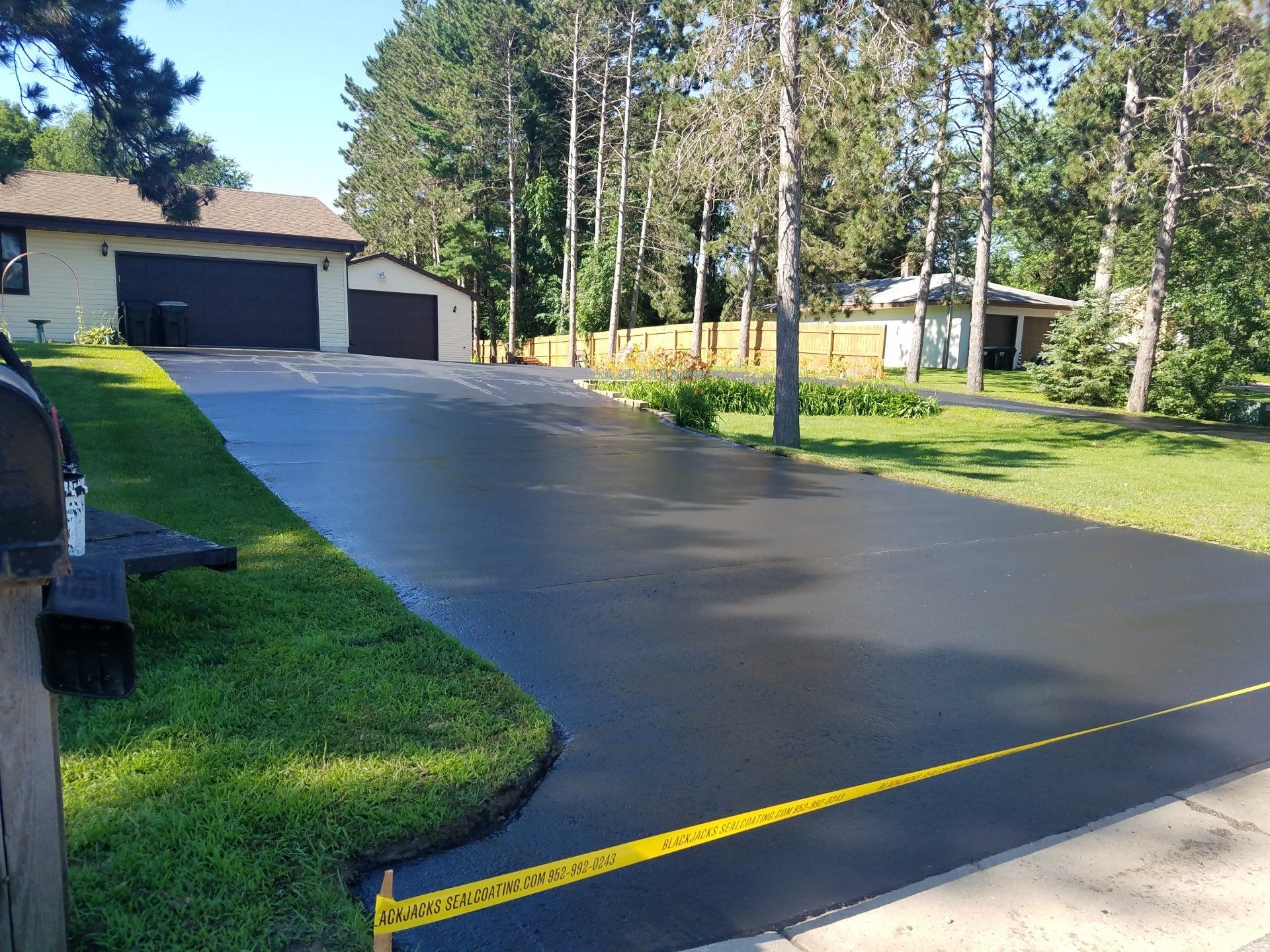 A driveway with a house in the background and trees on the side.