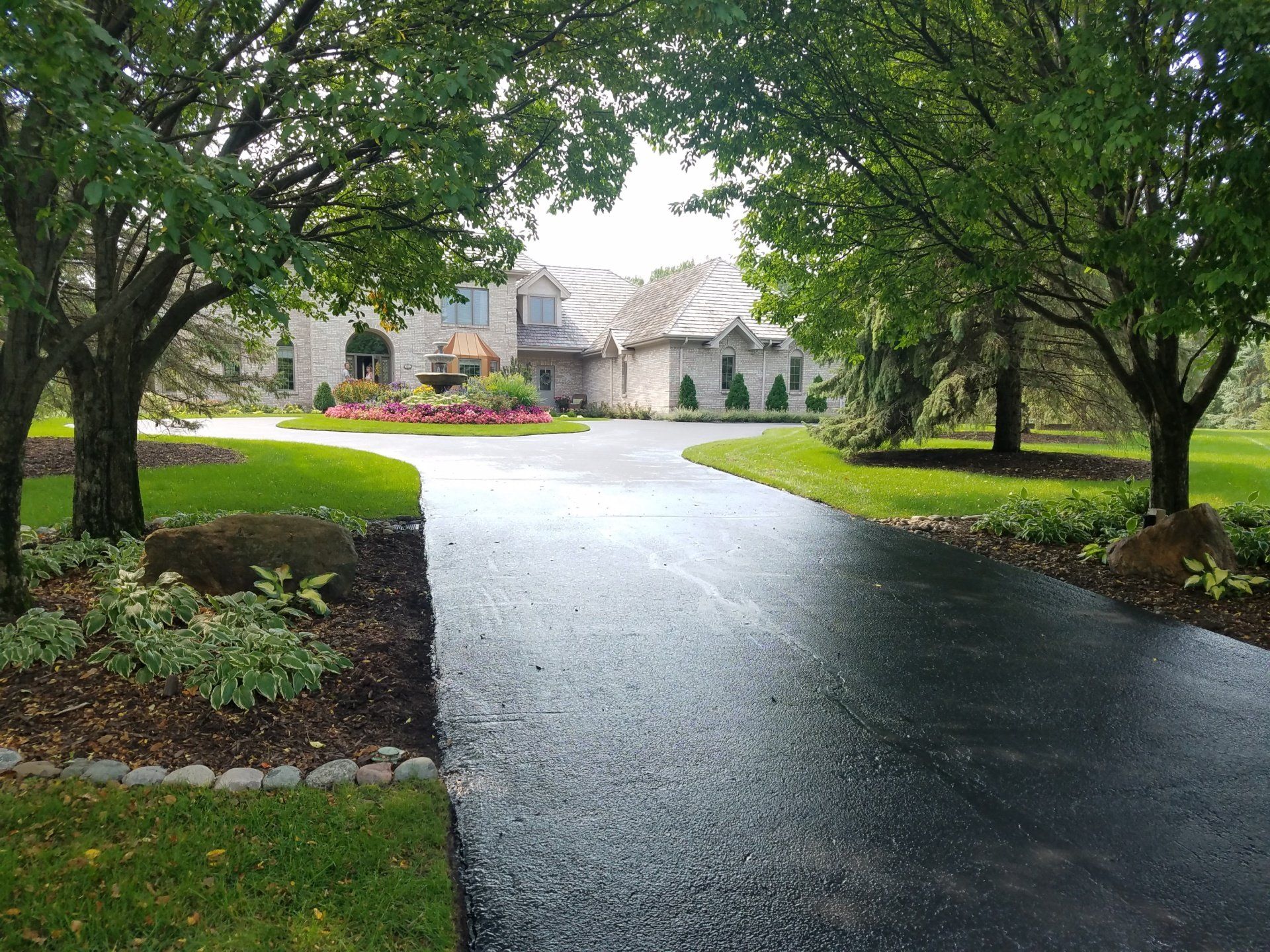 A driveway leading to a large house surrounded by trees.
