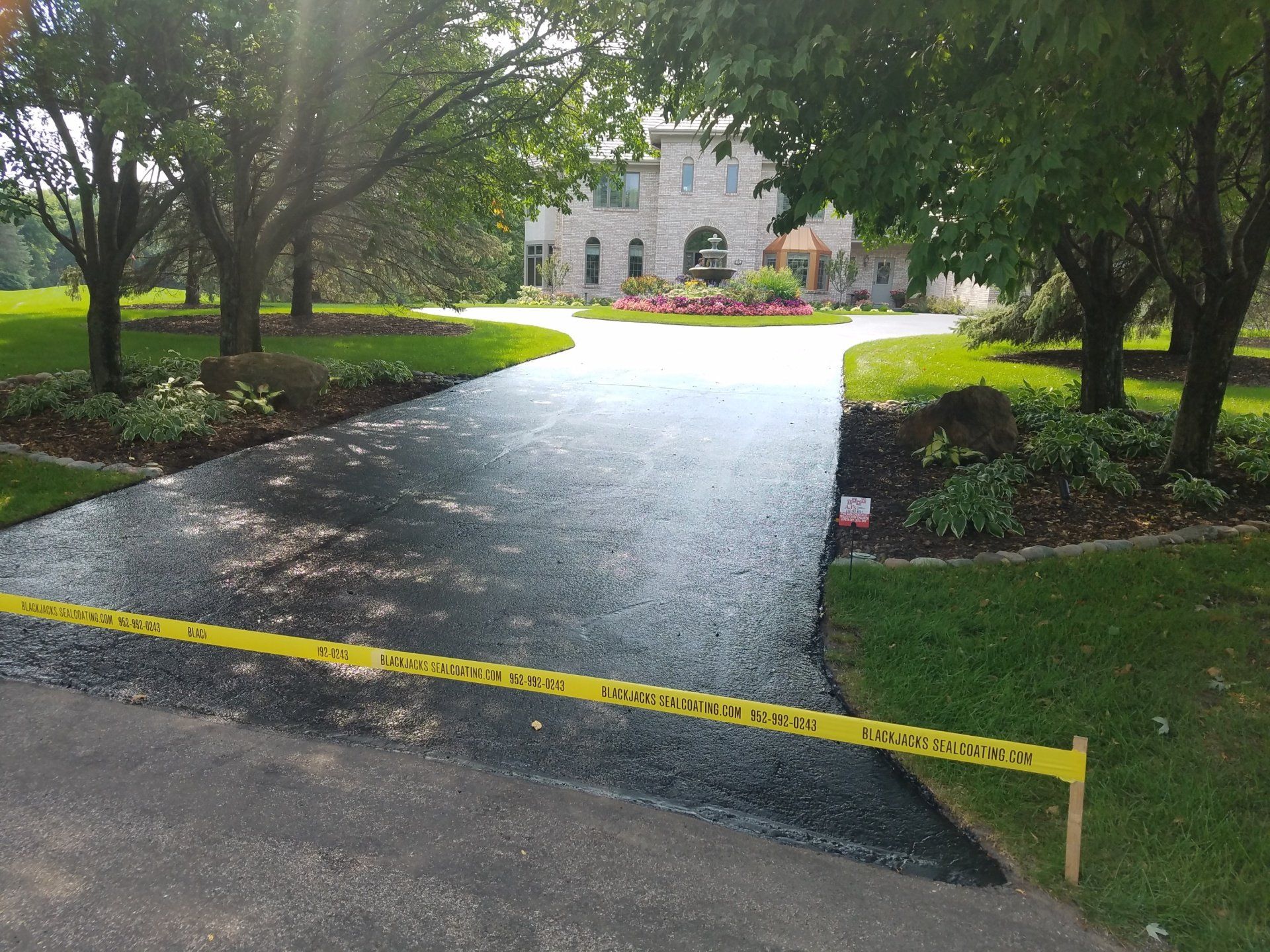 A driveway is being paved in front of a large house.