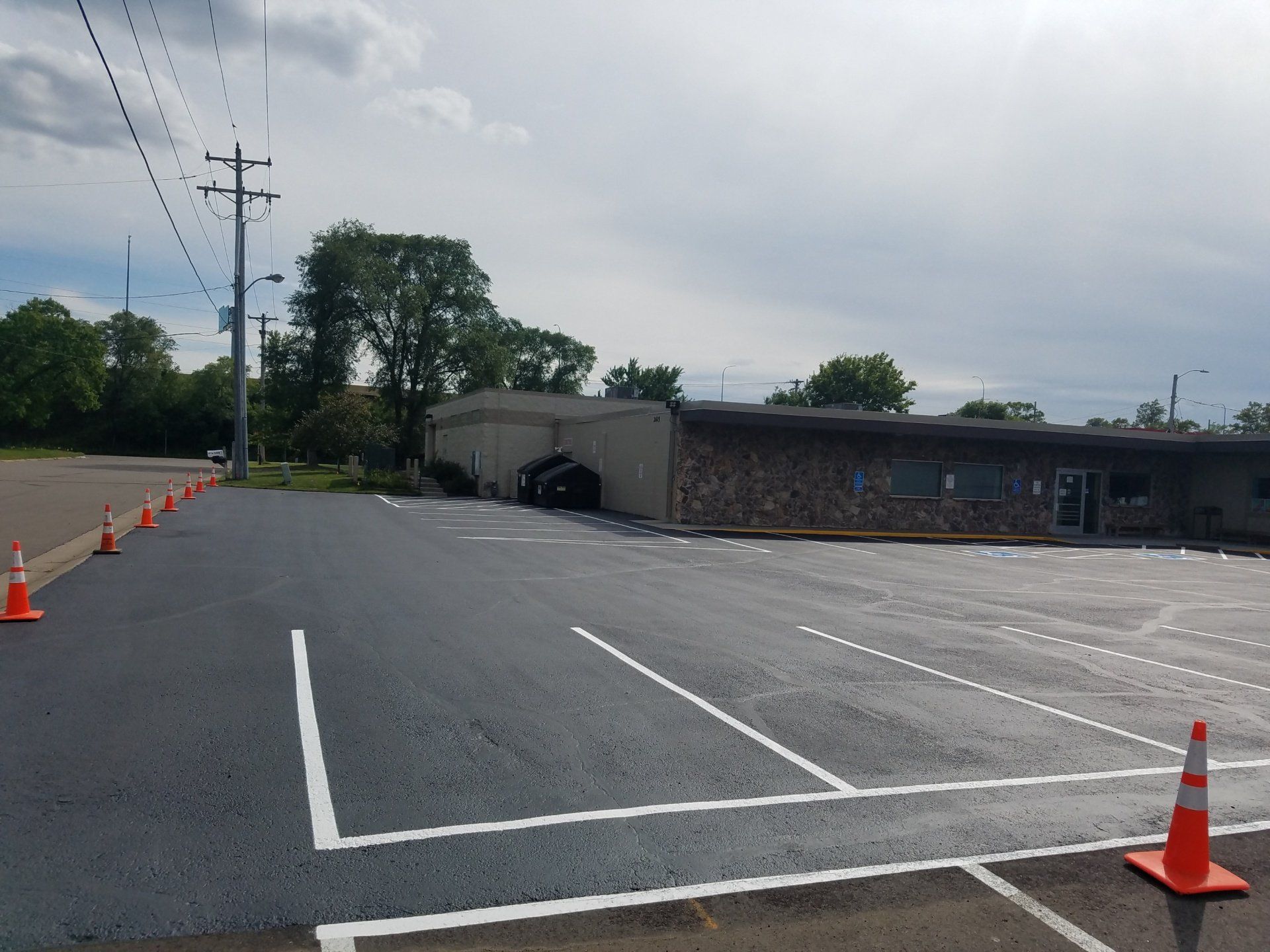 A parking lot with orange cones and a building in the background.