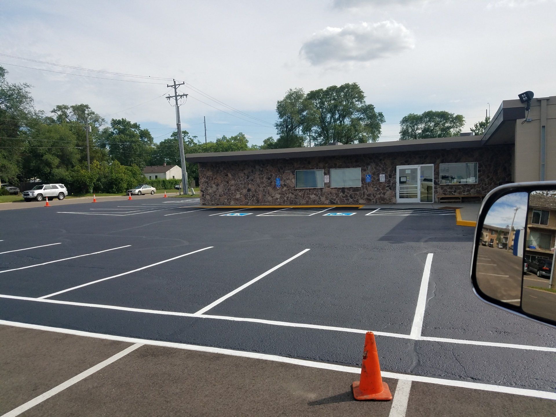 A parking lot with a building in the background and a traffic cone in the foreground.