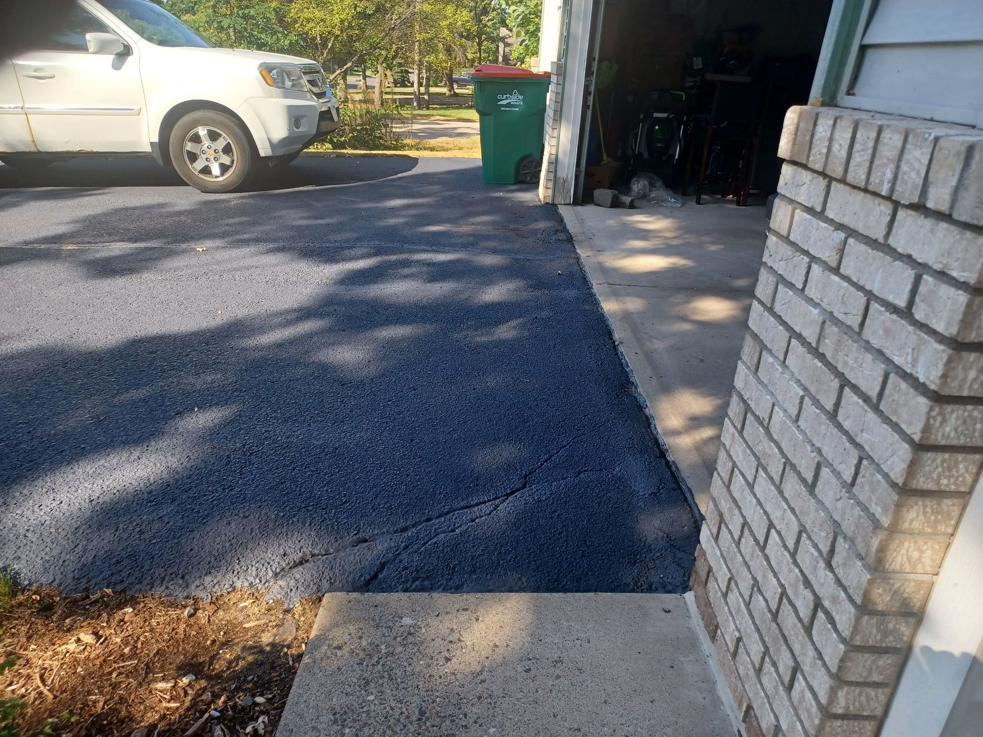 A white suv is parked in a driveway next to a brick wall.